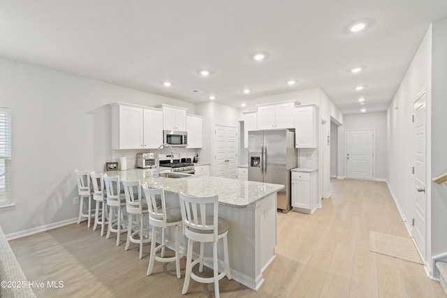 kitchen featuring white cabinetry, stainless steel appliances, kitchen peninsula, and a breakfast bar area