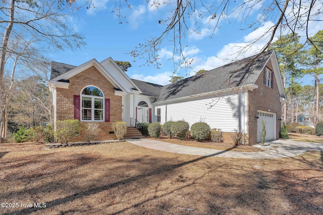 view of front facade featuring driveway, brick siding, crawl space, and an attached garage