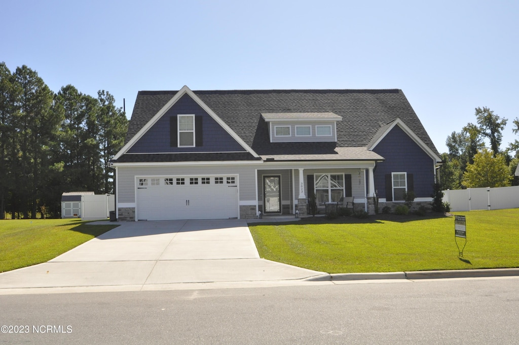 craftsman-style house featuring a garage, covered porch, and a front yard