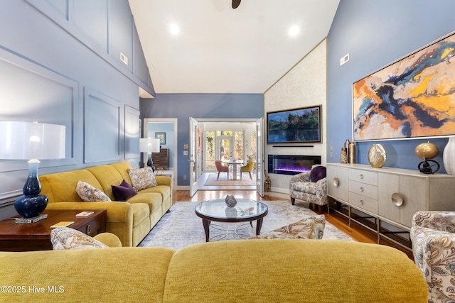 living room featuring a fireplace, light hardwood / wood-style flooring, and high vaulted ceiling