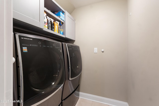 washroom featuring cabinets, washing machine and clothes dryer, and light tile patterned floors