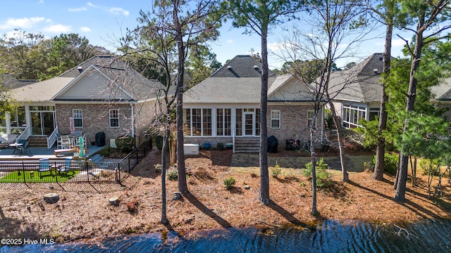 rear view of house featuring a water view, a patio, and a sunroom