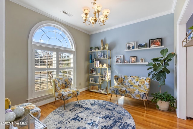 sitting room with hardwood / wood-style flooring, crown molding, and a chandelier