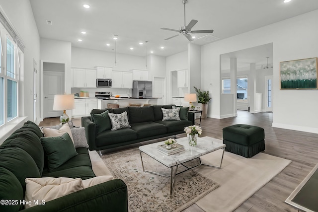 living room featuring hardwood / wood-style floors, a towering ceiling, a healthy amount of sunlight, and ceiling fan