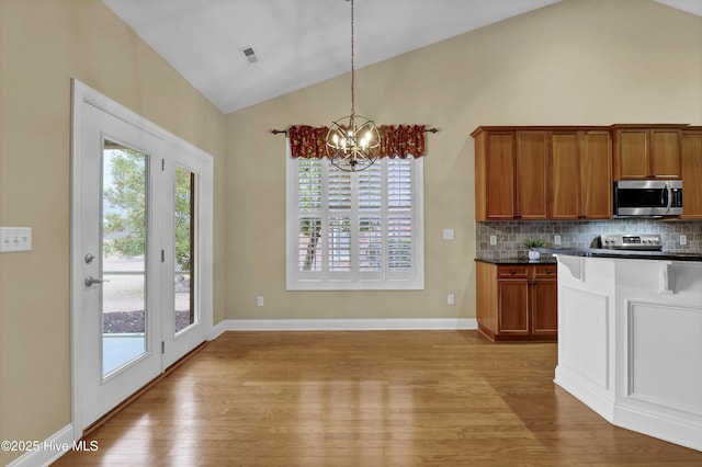 kitchen with dark countertops, lofted ceiling, visible vents, an inviting chandelier, and appliances with stainless steel finishes