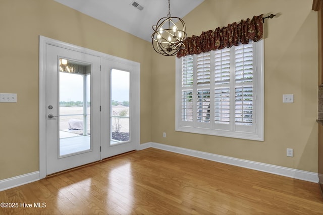 doorway to outside with baseboards, visible vents, wood finished floors, vaulted ceiling, and a notable chandelier