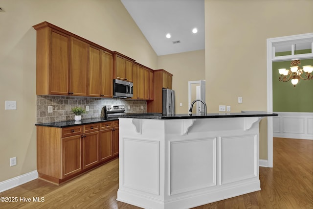 kitchen with appliances with stainless steel finishes, brown cabinetry, visible vents, and a kitchen bar