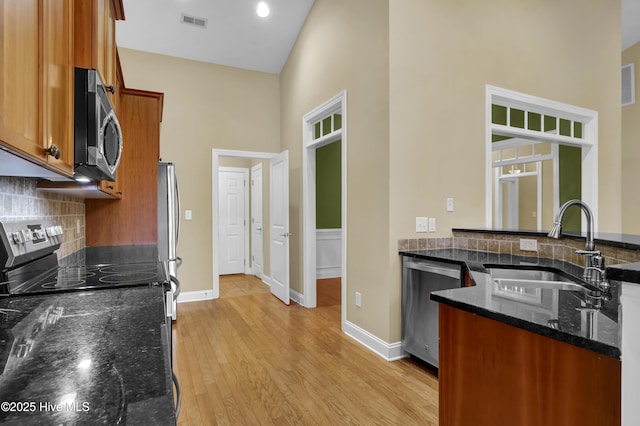 kitchen featuring light wood finished floors, visible vents, appliances with stainless steel finishes, brown cabinetry, and a sink