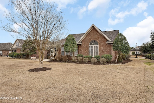 single story home featuring brick siding and roof with shingles