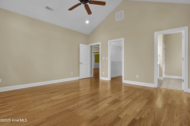 unfurnished bedroom with light wood-type flooring, a walk in closet, visible vents, and baseboards