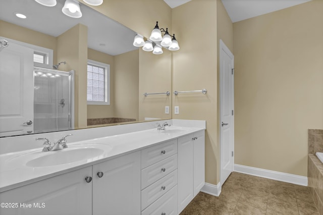 bathroom featuring double vanity, a shower with door, baseboards, and a sink