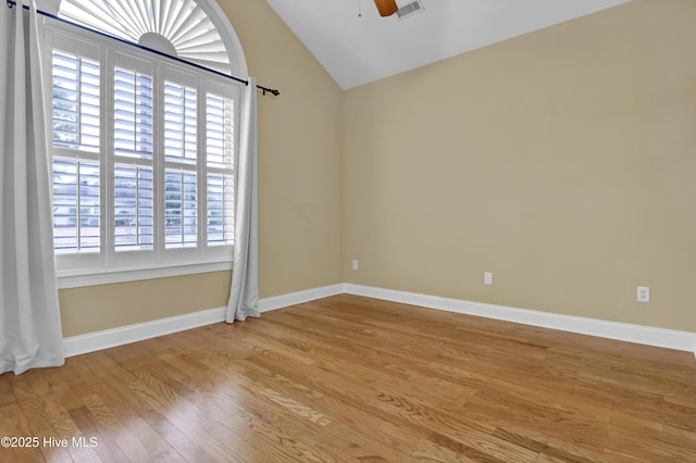 spare room with visible vents, vaulted ceiling, ceiling fan, light wood-type flooring, and baseboards