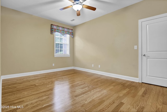 empty room featuring light wood finished floors, a ceiling fan, visible vents, and baseboards