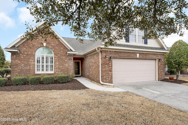 traditional-style house featuring concrete driveway, brick siding, roof with shingles, and an attached garage