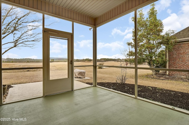 unfurnished sunroom featuring a wealth of natural light and a rural view