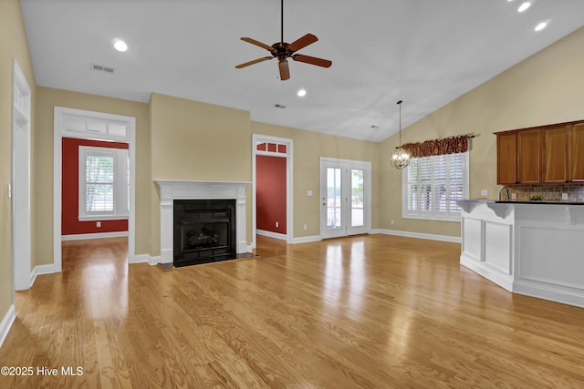 unfurnished living room with lofted ceiling, light wood finished floors, a fireplace with flush hearth, and visible vents