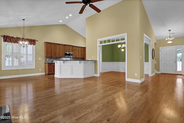 kitchen with dark wood-style floors, stainless steel microwave, open floor plan, and brown cabinetry