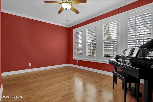 sitting room with wood finished floors, a ceiling fan, visible vents, baseboards, and ornamental molding