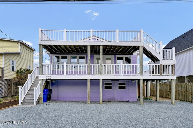 back of property featuring gravel driveway, an attached garage, fence, a carport, and stairs