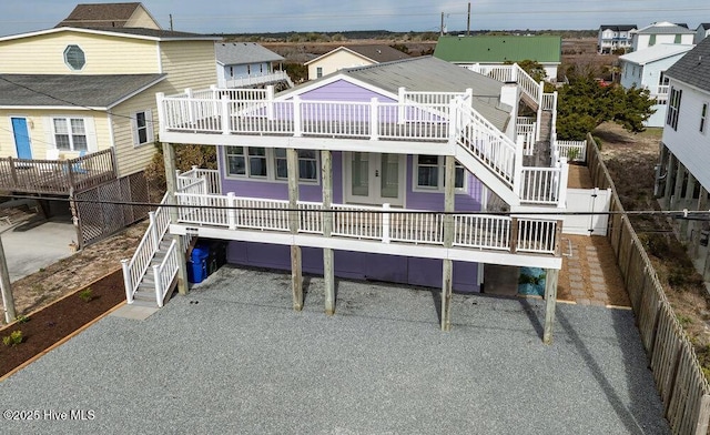 back of house featuring a residential view, fence, and stairway