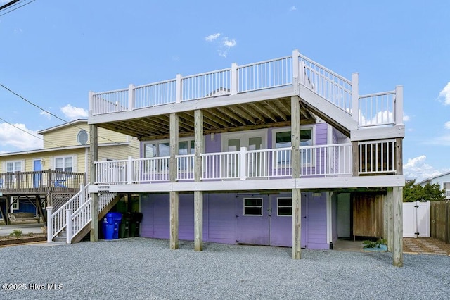 rear view of property featuring a carport, gravel driveway, and stairway