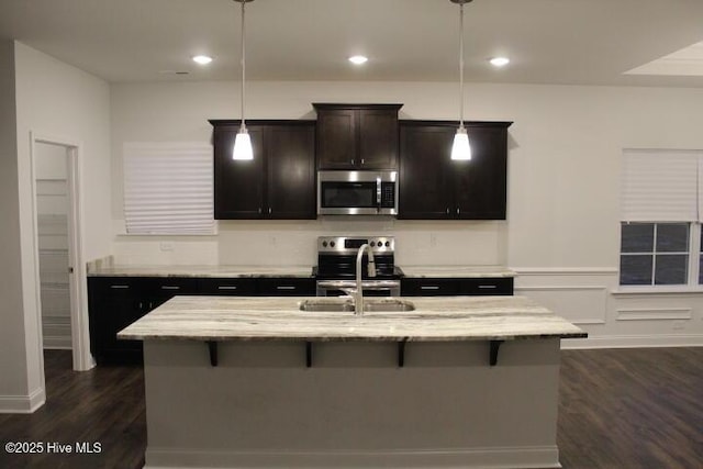 kitchen with appliances with stainless steel finishes, sink, an island with sink, and hanging light fixtures