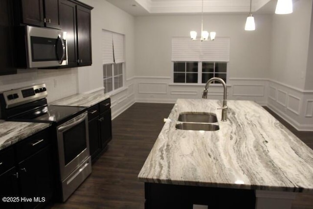 kitchen featuring light stone counters, sink, an island with sink, and appliances with stainless steel finishes