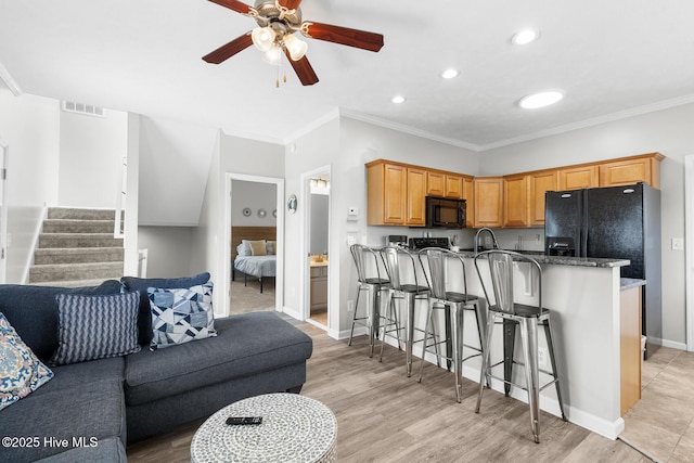 kitchen featuring crown molding, light hardwood / wood-style floors, a breakfast bar, and kitchen peninsula