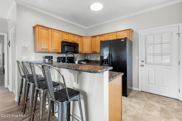 kitchen with a breakfast bar, crown molding, kitchen peninsula, dark stone counters, and black appliances