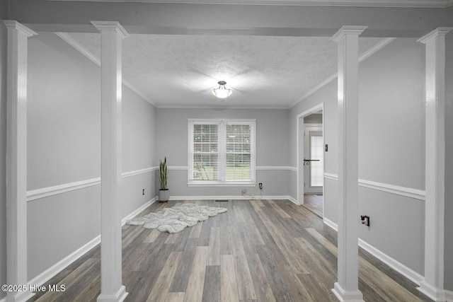 spare room featuring decorative columns, crown molding, hardwood / wood-style floors, and a textured ceiling