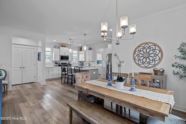 dining area with a notable chandelier, recessed lighting, light wood-type flooring, and crown molding