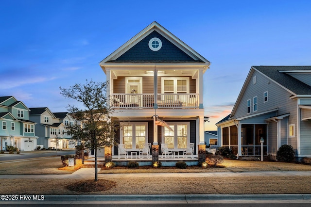 view of front of property featuring a porch, a residential view, a balcony, and a sunroom