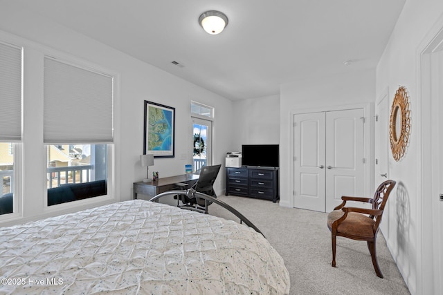 bedroom featuring multiple windows, visible vents, a closet, and light colored carpet