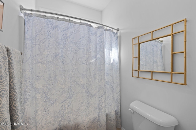 bathroom with a shower with shower curtain and toilet