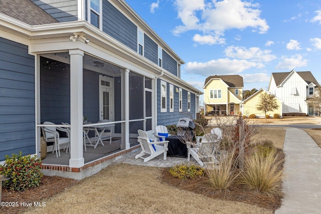 view of home's exterior featuring roof with shingles, a residential view, and a sunroom