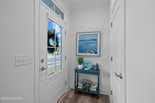 doorway to outside featuring crown molding, baseboards, and wood finished floors