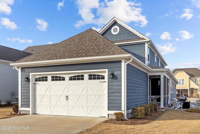 view of side of property featuring concrete driveway, a shingled roof, and an attached garage