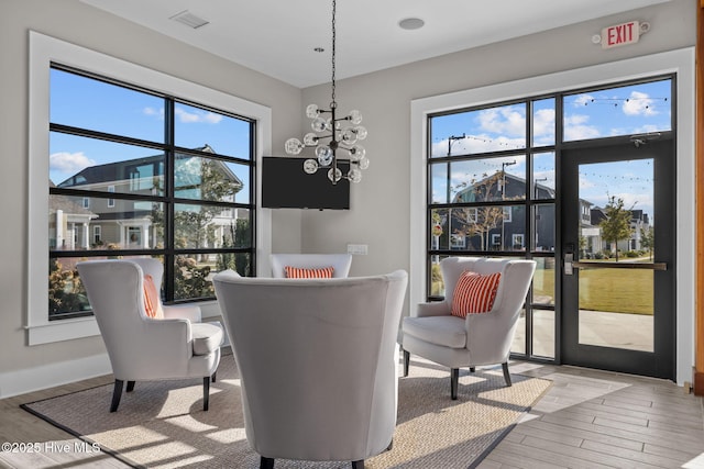 dining area featuring visible vents, a notable chandelier, baseboards, and wood finished floors