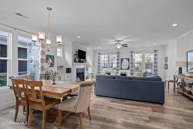 dining room with recessed lighting, a fireplace, visible vents, light wood finished floors, and crown molding