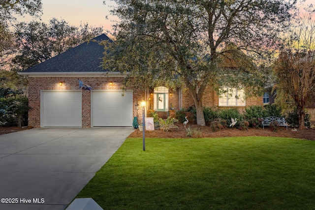 view of front of property featuring brick siding, concrete driveway, a front yard, roof with shingles, and an attached garage