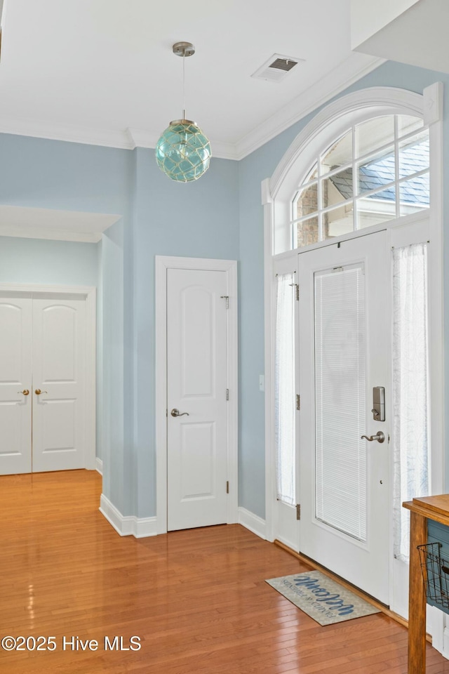 entryway with crown molding, baseboards, visible vents, and light wood finished floors