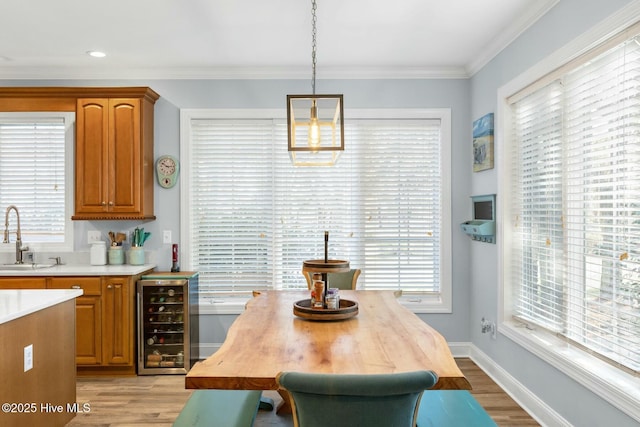 dining area featuring ornamental molding, sink, wine cooler, and light hardwood / wood-style flooring