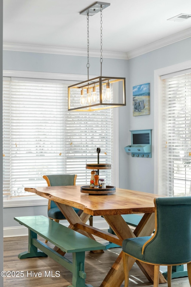 dining room featuring baseboards, wood finished floors, visible vents, and ornamental molding