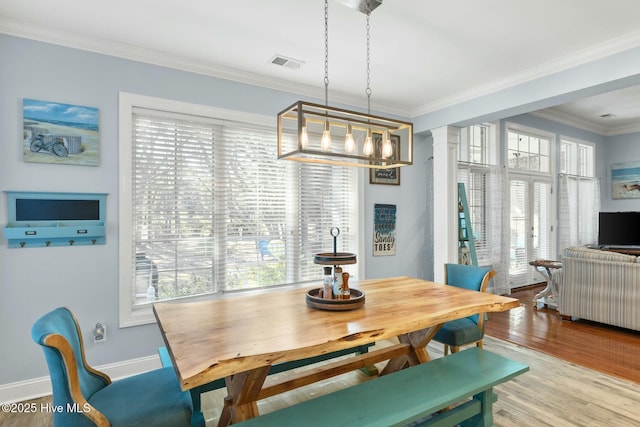 dining space with visible vents, crown molding, baseboards, wood finished floors, and ornate columns