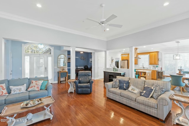 living room with a healthy amount of sunlight, ornamental molding, and ornate columns