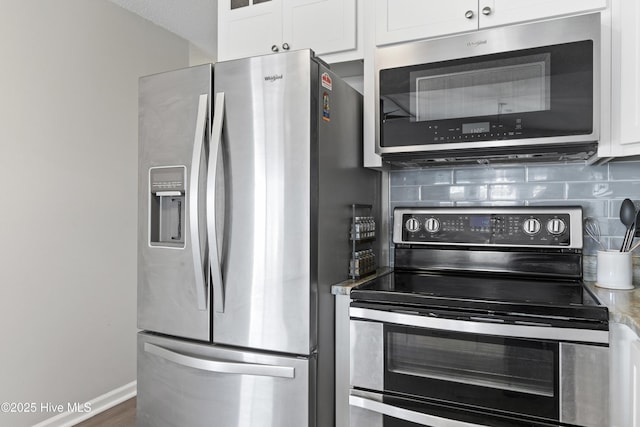 kitchen featuring stainless steel appliances, baseboards, white cabinets, and decorative backsplash