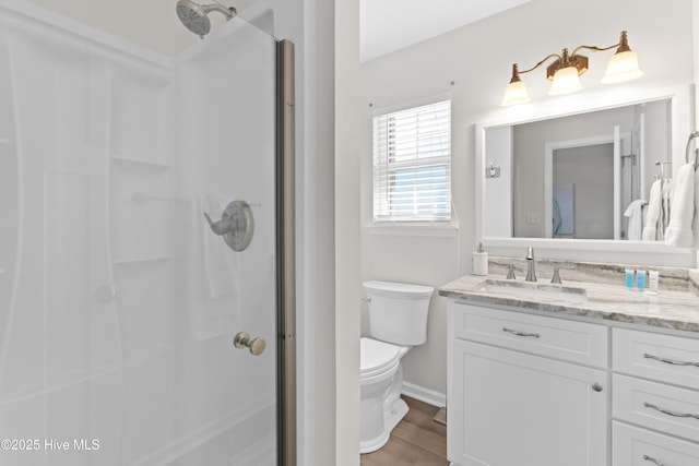 bathroom with toilet, an enclosed shower, wood finished floors, and vanity