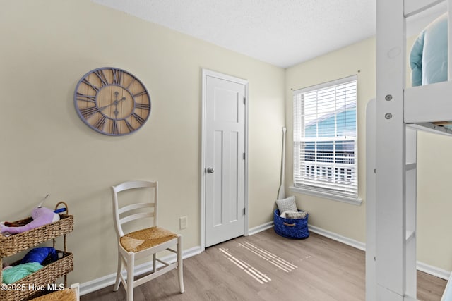 living area with light wood-type flooring, baseboards, and a textured ceiling