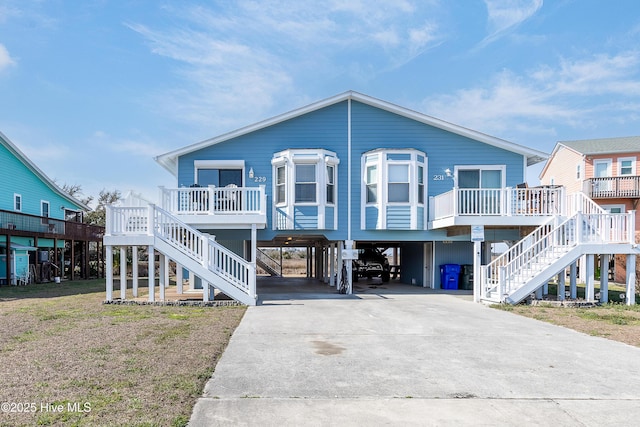 beach home featuring covered porch, stairway, a carport, and concrete driveway