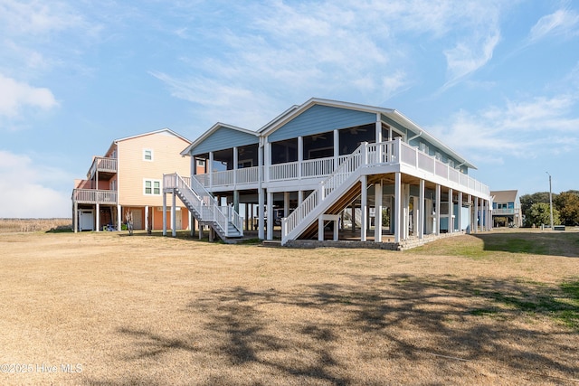 rear view of property featuring a lawn and stairway